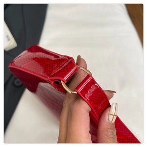 Detailed view of red snakeskin textured leather handbag with gold metal hardware ring
