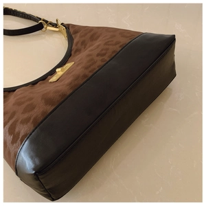 Detail view of leopard print crossbody bag with black leather trim and gold buckle accents