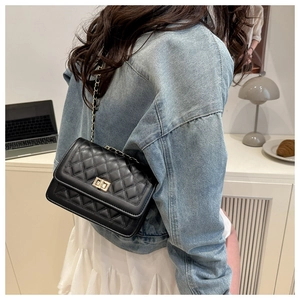 Close-up of a black quilted crossbody bag with gold hardware and chain strap on a model