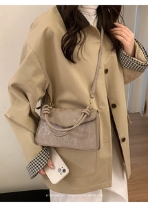 Detail of coffee-colored textured crossbody bag with unique knot handle and wavy surface