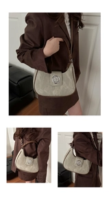 Detail of a beige suede underarm bag with a brown leather handle and metal M logo