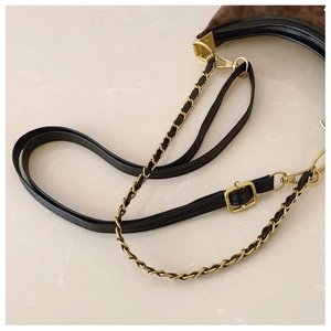 Detail of crossbody bag showing brown suede, black leather straps and gold metal chain