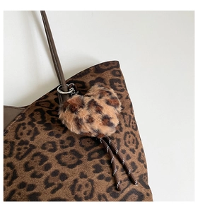 Detailed view of heart-shaped leopard print plush keychain with braided strap on bag