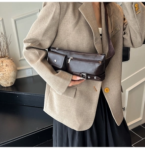 Detail of dark brown pebble leather sling bag with multiple pockets and silver hardware