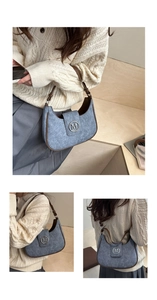 Detail of blue denim crescent bag with brown leather piping and metallic M logo