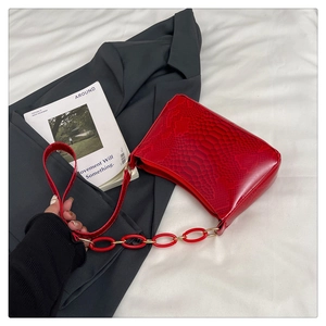 Detail of red crocodile texture handbag with trendy oversized resin chain strap