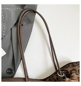 Close-up of leopard print shoulder bag with plush fur texture and pompom charm