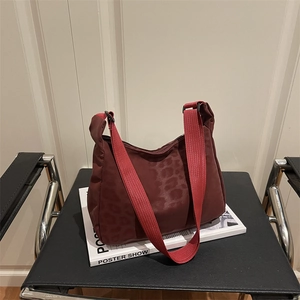 Burgundy leopard print underarm bag with bright red strap in a crescent shape