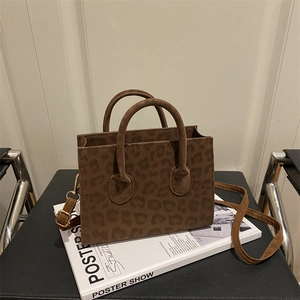 Elegante borsa tote leopardata con hardware dorato e tracolla regolabile su sedia