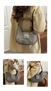 Detail of grey crescent shoulder bag featuring brown leather trim and silver metal M logo