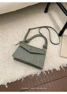 Detail of green pleated crossbody bag with gold hardware and knotted shoulder strap