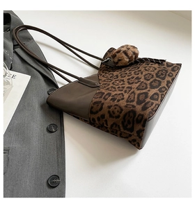 Detail view of large leopard print tote bag with brown leather trim and fuzzy charm