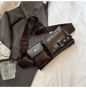 Detailed view of dark brown leather utility chest bag with buckles and nylon strap