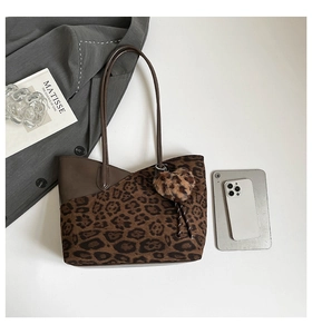 Detailed view of leopard print tote bag with plush heart charm and faux leather straps