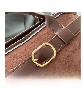 Close-up of brown suede and leather texture with golden metal buckle and fine stitching