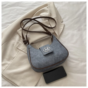 Detail of grey fabric crescent bag with brown leather trim and silver metal M logo buckle