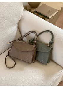 Detail of trendy crossbody flap bag with textured leather and unique knotted handle