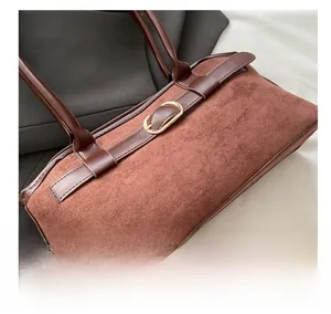 Detail of vintage brown suede handbag featuring a gold horseshoe metal buckle and leather strap