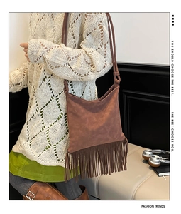 Close-up of brown suede shoulder bag featuring long fringe tassels and vintage design