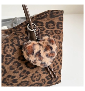Close-up of heart-shaped leopard print plush charm attached to a stylish leopard shoulder bag