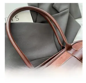 Detail showing the stitching craftsmanship and metal adjustment buckle on the suede handbag