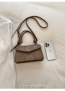 Detailed view of the vertical ribbed texture and circular handle on a brown crossbody bag