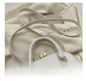 Detailansicht der gewebten weißen Muscheltasche mit Gold-Reißverschlüssen und Metallteilen
