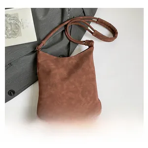 Detail of brown suede crossbody bag featuring long fringes and bohemian tassel design