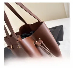Detailed close-up of brown leather tote with fine stitching and metal buckle accents