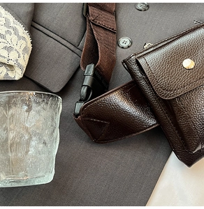 Close-up of brown pebbled leather texture on a retro crossbody chest bag with metal buckle