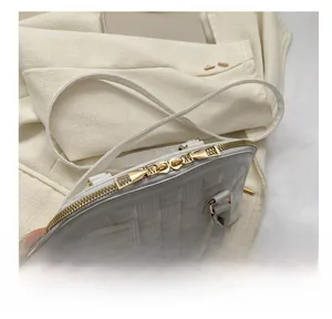Detail des glatten goldenen Doppelreißverschlusses und der Webstruktur der beigen Handtasche