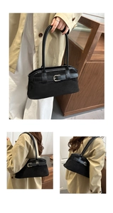 Detail of vintage suede shoulder bag in black featuring metal buckle and dual straps