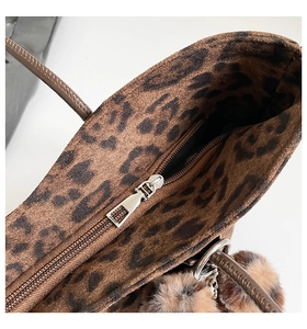 Detail shot of leopard print tote bag interior featuring metal zipper and plush charm