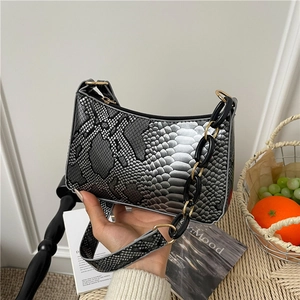 Silver snakeskin textured underarm bag with elegant chain strap in a lifestyle setting