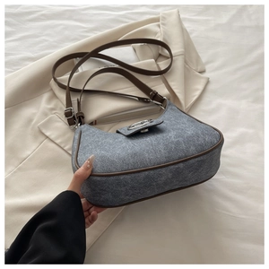 Detail of grey wool fabric texture and brown leather trim on a crescent underarm bag