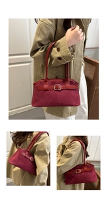 Detail of wine red suede handbag with decorative gold buckles and dual handle design