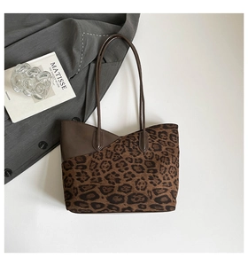 Close-up of leopard print tote bag featuring brown leather trim and long shoulder straps