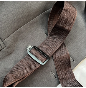 Detail of adjustable nylon strap and metal buckle on a twill fabric shoulder bag