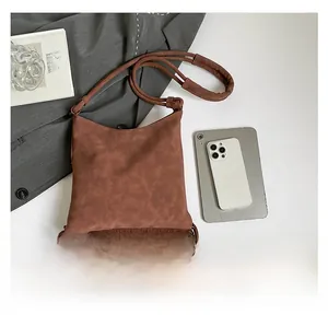 Detailed view of dark brown bohemian crossbody bag with long fringes and braided strap