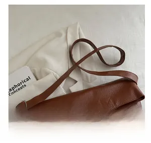 Detailed macro view of the brown leather texture and adjustable strap on the tote bag