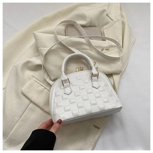 Detalle de bolso tipo concha blanco con cremallera dorada y piel sintética texturizada
