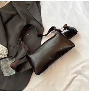 Detail of dark brown lychee textured leather chest bag with adjustable nylon strap
