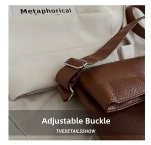 Detail of adjustable metal buckle on a brown leather tote bag with a textured finish