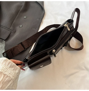 Detail of dark brown lychee grain leather crossbody bag with silver zippers and wide strap