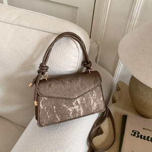 Petit sac à main marron rétro avec imprimé doré sur un canapé au style épuré