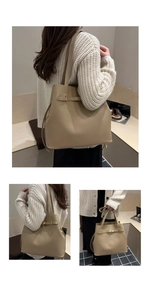 Detail of minimalist beige leather bucket bag with gold buckle and adjustable shoulder strap