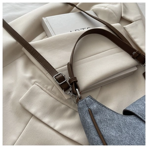 Detailed close-up of the grey textured saddle bag with brown leather strap and silver buckle