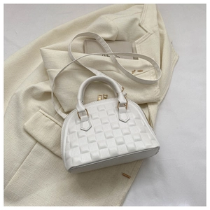 Detalle del bolso tipo concha blanco con relieve de cuadrícula y herrajes dorados