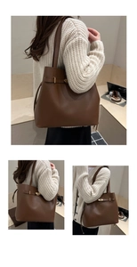 Detail of a brown leather bucket bag with gold clasp and long handles for shoulder wear