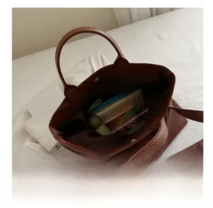 Top view of large brown leather tote bag interior showing spacious capacity for books